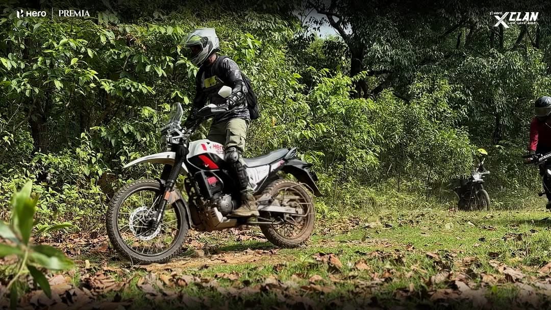 Barik Da riding a Hero trail motorcycle through a forest route