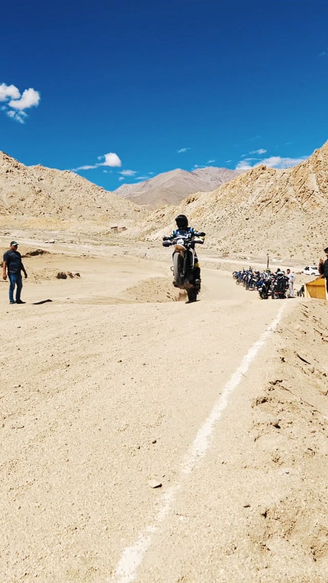 Barik Da riding a wheelie on a high-altitude mountain road